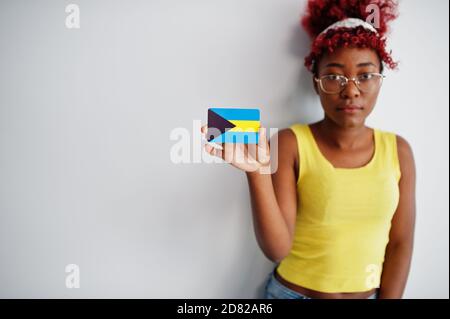 African american woman with afro hair, wear yellow singlet and eyeglasses, hold Bahamas flag isolated on white background. Stock Photo