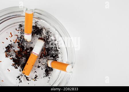cigarette butts in an ashtray on a white background, top view, copy space. Stock Photo