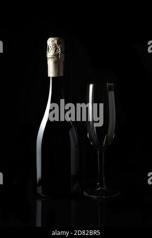 Sparkling wine with an empty glass on a dark background. Stock Photo