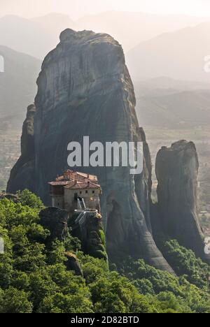 view of a monastery tower on top of a rock Meteora in haze evening Stock Photo