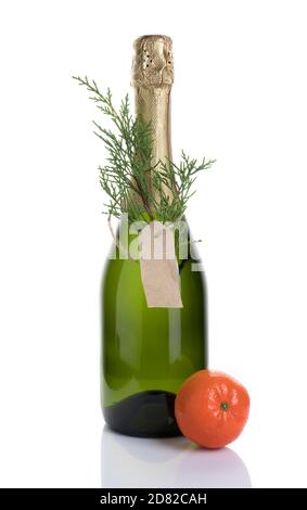 Christmas alcoholic background with a bottle of champagne decorated with a coniferous branch and a tangerine on a light background. Stock Photo