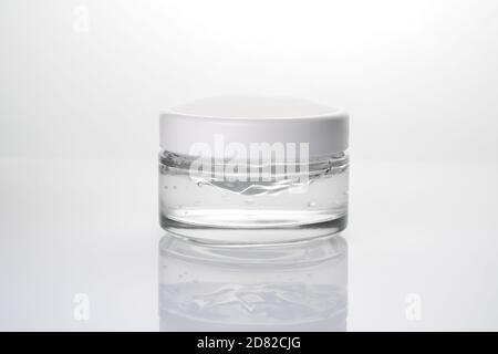 Glass jar with cream close-up on a light glossy background. Stock Photo