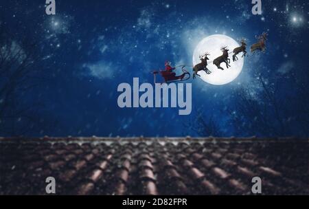 Santa Claus on his sleigh, pulled by reindeer, flying at night to deliver gifts Stock Photo