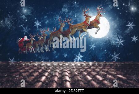 Santa Claus on his sleigh, pulled by reindeer, flying at night to deliver gifts Stock Photo