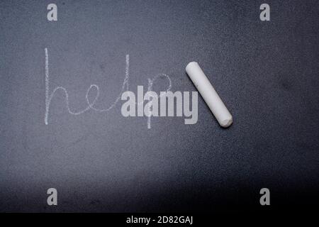 Help word written in chalk on a black chalkboard. Stock Photo