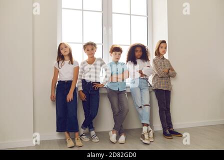 Group of diverse friends standing by the window and looking at the camera in the hallway. Stock Photo