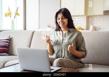 Indian woman online teacher talking by video call using laptop at home. Stock Photo