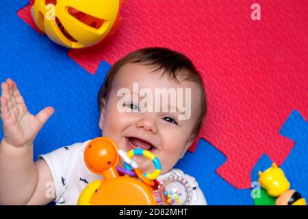 Funny baby playing on colorful eva rubber floor. Toddler having fun indoor his home. Top view. Stock Photo