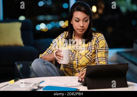 Latin American Woman Working from Home At Night Stock Photo