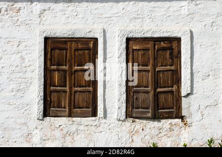 two windows of wooden on the whitewashed wall of a greek house Stock Photo