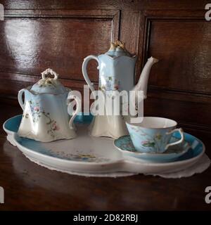 An antique porcelain service - a teapot, two cups and saucers in blue and white with flowers - stands on the chest of drawers. Stock Photo