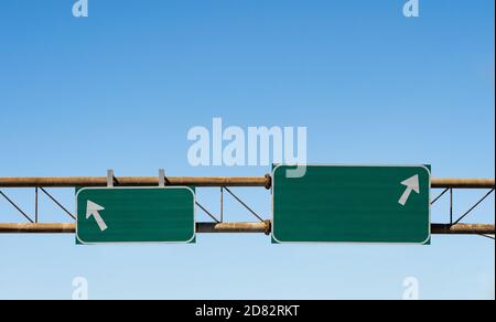 blank overhead highway signs in green and white with arrows pointing in opposite directions Stock Photo