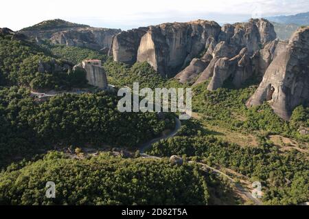 winding road crosses the landscape of the Meteora to go to the Roussanou monastery Stock Photo