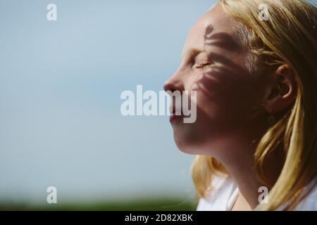ittle girl has grass shadow on her face Stock Photo