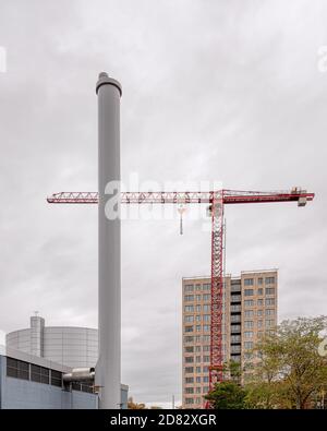 apartment block behind a heating plant chimney with a red construction-crane, Frederikssund, Denmark, October 25, 2020 Stock Photo