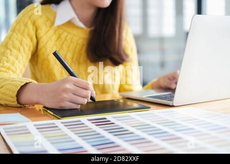 Graphic designer working with color samples for selection. Graphic designer at work. Color swatch samples. Young photographer and graphic designer at Stock Photo