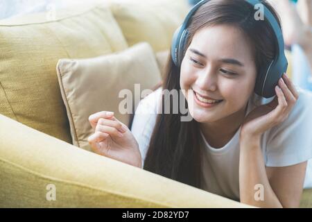 Young woman listening to music  lying on sofa in room. Stock Photo