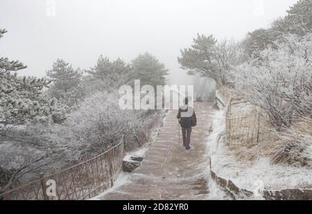 The traveler man walking on the walk way and plenty of the snow cover all of the area on the Huangshan mountain in the winter season, It’s cold. Stock Photo