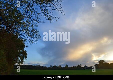 Decaying storm clouds in clear sky autumn evening Downe, Kent, once home to Charles Darwin. Clouds luminous and glowing as sun sets beautiful sky Stock Photo