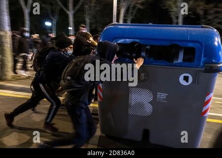 A group of hooded youths are seen dragging rubbish containers to form a barricade on Passeig de Picasso during the demonstration.About 300 people have gathered in Plaza de Sant Jaume to demand concrete and effective policies to face the economic crisis produced by the Covid-19 pandemic after the declaration of the state of exception and the night curfew decreed by the Government. The demonstration finally ended with the intervention of the riot police after some riots broke out. Stock Photo