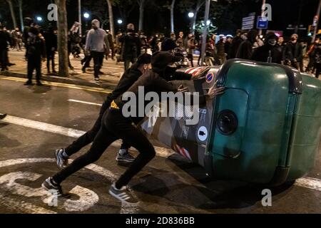 A group of hooded youths are seen dragging rubbish containers to form a barricade on Passeig de Picasso during the demonstration.About 300 people have gathered in Plaza de Sant Jaume to demand concrete and effective policies to face the economic crisis produced by the Covid-19 pandemic after the declaration of the state of exception and the night curfew decreed by the Government. The demonstration finally ended with the intervention of the riot police after some riots broke out. Stock Photo