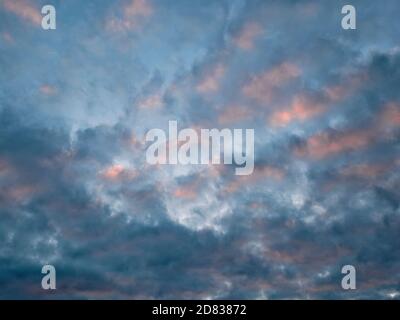 Abstract image of pink and orange clouds against a blue sky at sunset. Stock Photo