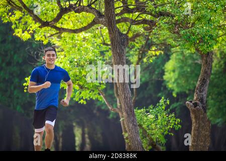 Young man in fitness wear and running in the park Stock Photo