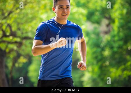 Young man in fitness wear and running in the park Stock Photo