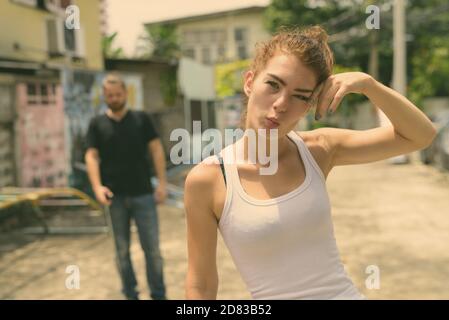 Young beautiful teenage girl making funny face with young bearded man in the old playground Stock Photo