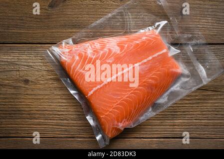 Fresh raw salmon fish steak on wooden background / Salmon fillet packaged in plastic vacuum pack in packing sell in supermarket Stock Photo