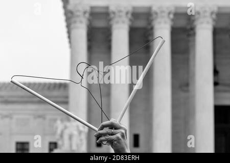 Washington, DC, USA, 26 October,  2020.  Pictured: A woman stood at the Supreme Court for the better part of an hour holding coathangers against the backdrop of the Supreme Court while protesting against the confirmation of Amy Coney Barrett and in favor of reproductive, civil, and women's rights.  This was part of Refuse Fascism's  protest just hours before Barrett was confirmed by the U.S. Senate.  Credit: Allison C Bailey/Alamy Live News Stock Photo