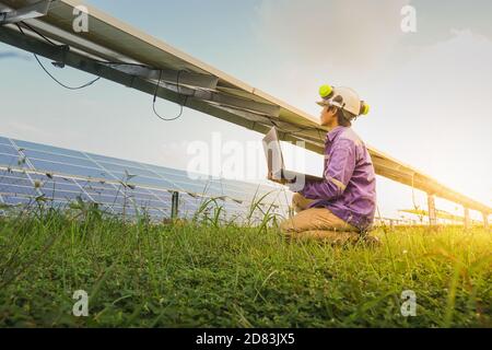 The low angle view of the solar farm and the engineers are using the computer to check the operation of the system, Photovoltaic module idea for clean Stock Photo