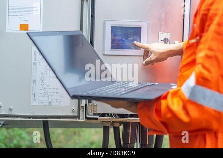 Engineers used a laptop for checking the performance of the controller box to confirming systems working normally. Concepts professional engineer for Stock Photo