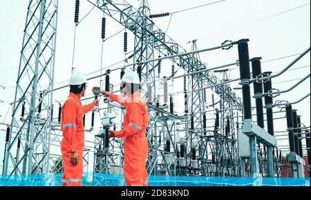 Electrical engineers used a thermometer to check for faults in equipment sets, Also known as preventive maintenance to reduce the damage of equipment, Stock Photo