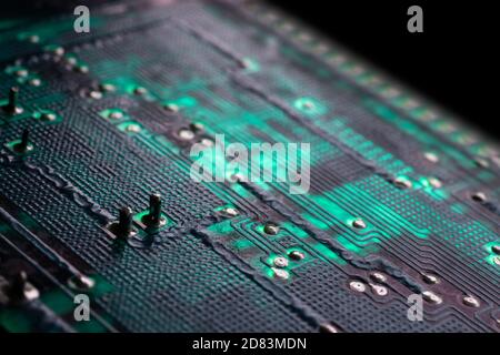 Green electronic circuit board with many electrical components. Narrow depth of field, focus on the left part of the image. Isolated on black Stock Photo