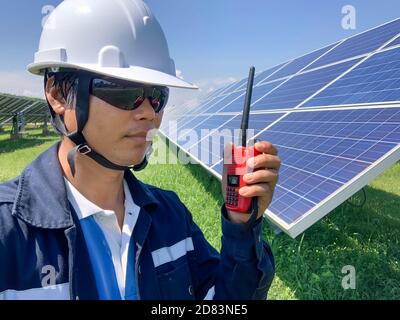 Construction engineers use a walkie-talkie to communicate with technicians in solar power plants. Concept of the solar cells is alternative energy to Stock Photo