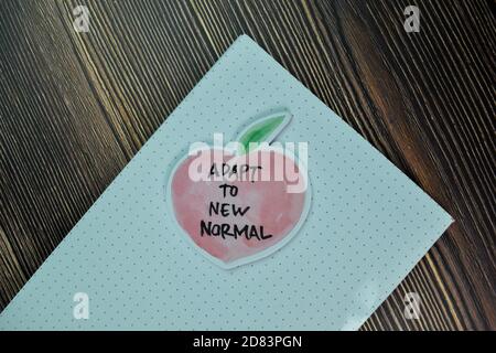 Adapt to New Normal write on sticky note and isolated on Wooden Table. Finance Concept Stock Photo