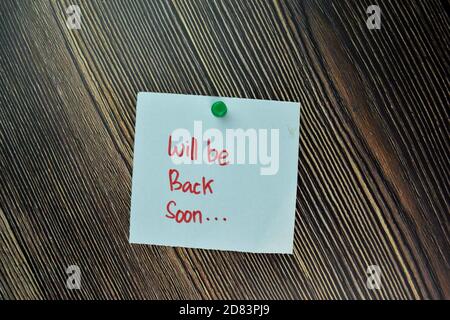 Will be Back Soon write on sticky note and isolated on Wooden Table. Business Concept Stock Photo