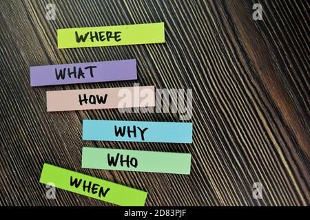 Where, What, How, Why, Who, When write on sticky note and isolated on Wooden Table. Stock Photo