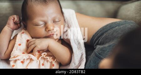 Upper view photo of a sleeping baby held by her mother on hands Stock Photo