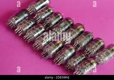Group of random radio tubes on a pink background. Vacuum tubes of various sizes and powers. Obsolete radio parts. Collecting. Selective focus. Stock Photo