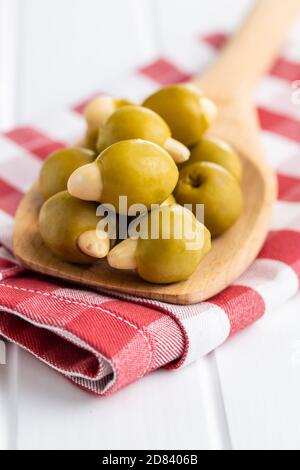 Pitted green olives stuffed with almonds on wooden spoon on checkered napkin. Stock Photo