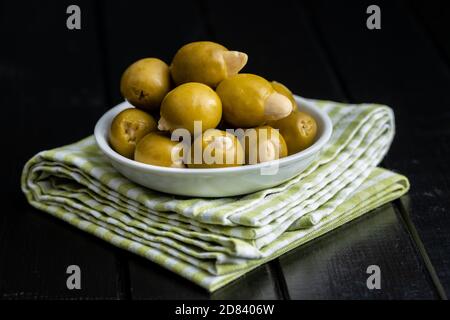 Pitted green olives stuffed with almonds in bowl on checkered napkin. Stock Photo