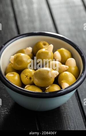Pitted green olives stuffed with almonds in bowl on black table. Stock Photo