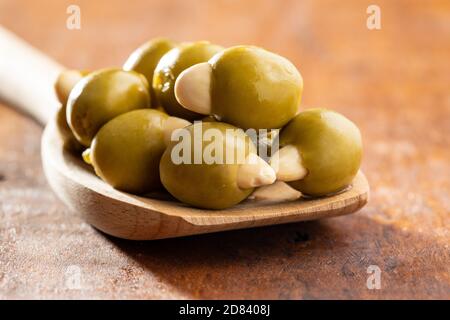 Pitted green olives stuffed with almonds on wooden spoon on wooden table. Stock Photo