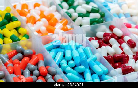 Colorful capsules pill in plastic box.  Pharmaceutical industry. Pharmacy drugstore products. Drug interactions. Healthcare and medicine background. Stock Photo