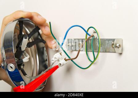 Male electrician connects the lamp on the wall. Stock Photo
