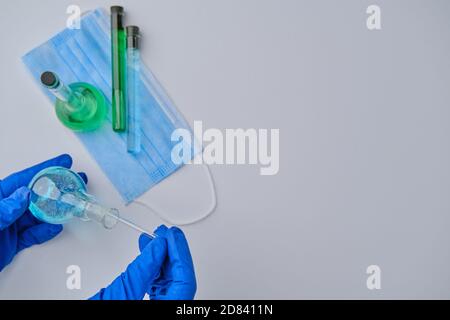 Scientist holding glass rod and flask at laboratory, closeup. Solution chemistry. Antivirus solution Stock Photo