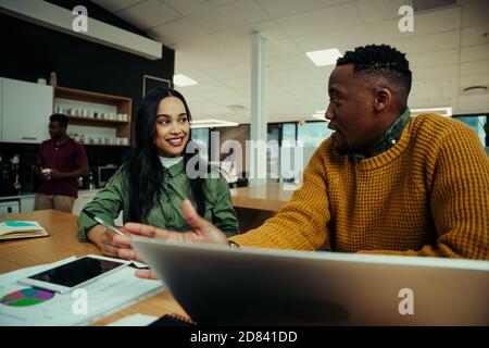 Indian woman discussing work with mixed race business man working in office foyer  Stock Photo