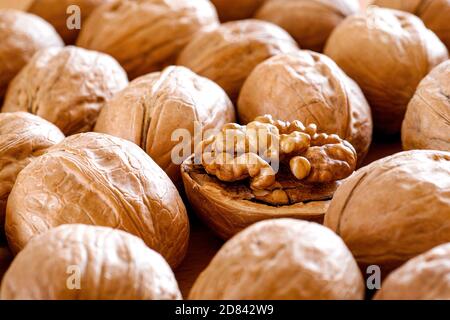 closeup of shelled walnut between walnuts in shell background pattern Stock Photo